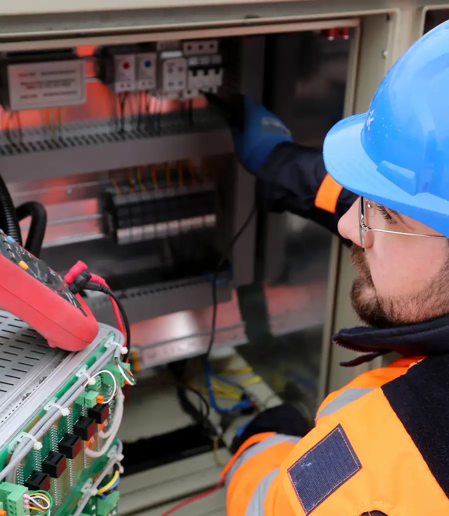 Utility field technician in hi-vis working inside an outdoor control cabinet